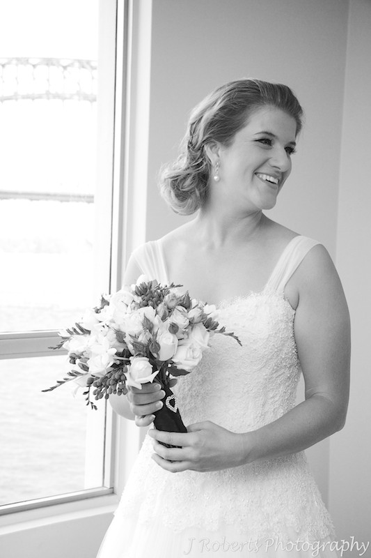 Bride holding bridal bouquet and smiling over her shoulder - wedding photography sydney